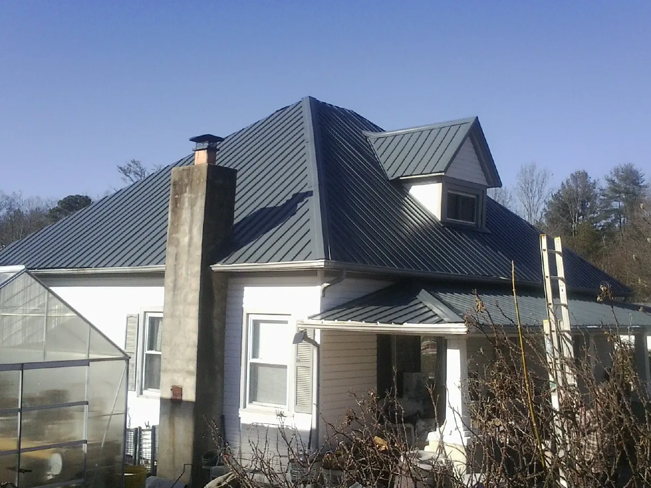 Dark blue standing seam metal roof on a white farmhouse with dormer — Slate & Tile Roof Repair by Roofing Brothers in Laguna Beach