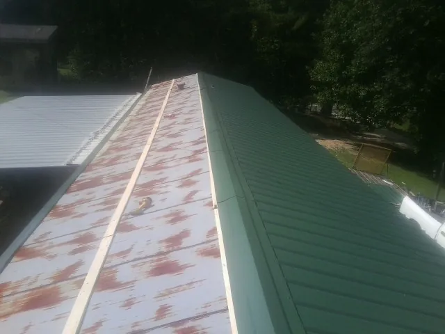 Old rusted panels beside newly installed green metal roofing — Wind Damage Roof Repair by Roofing Brothers in Laguna Beach