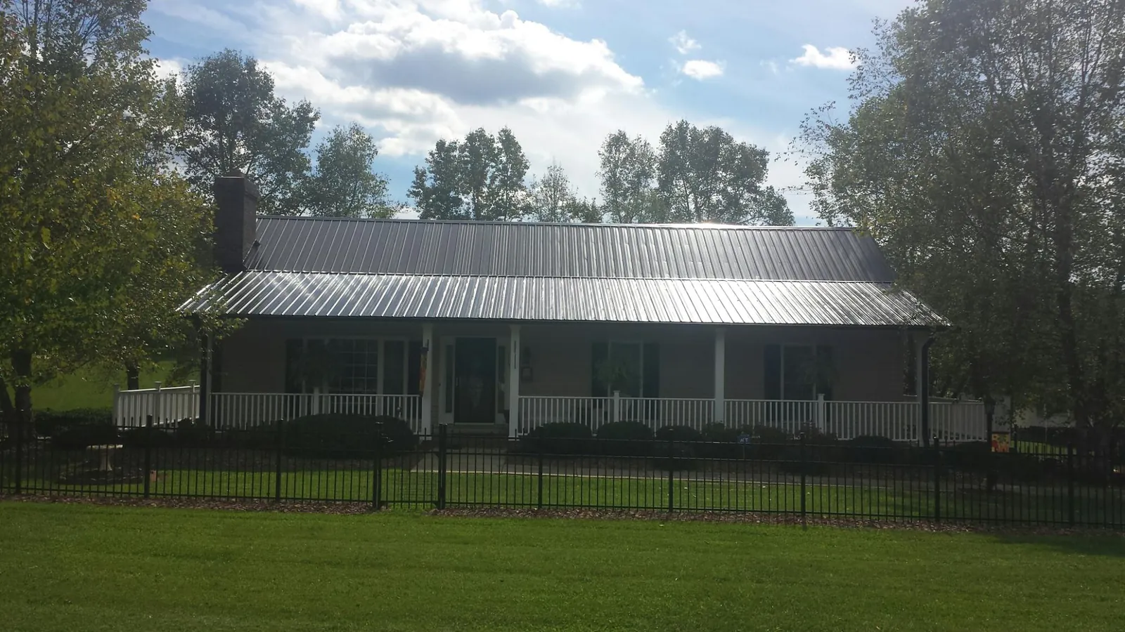 Gray metal roof on a brick ranch with a full width front porch — Gutter Guard Installation work by our crew in Laguna Beach