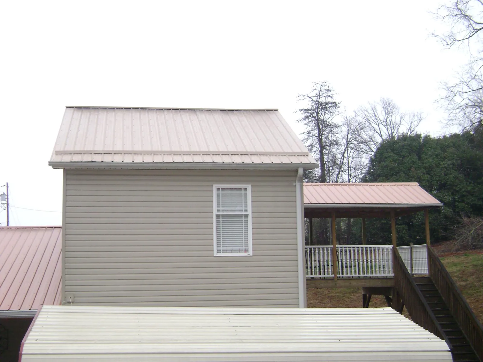 Tan metal roofs on a two story addition and attached porch, from a Roof Replacement job in Laguna Beach