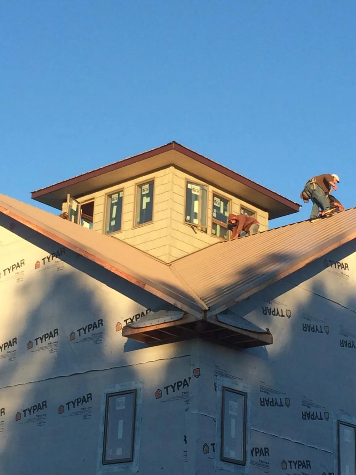 Roofers working around a rooftop cupola on a new metal roof at sunset — Roof Waterproofing in Laguna Beach by Roofing Brothers